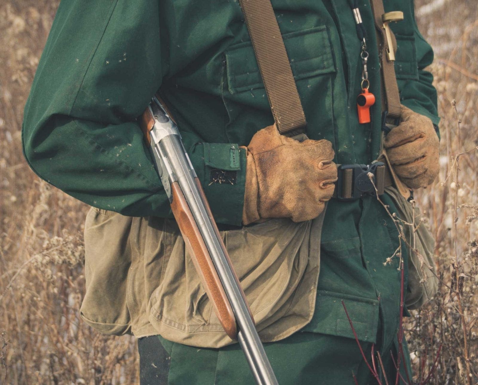 A bird hunter carries an over and under shotgun.
