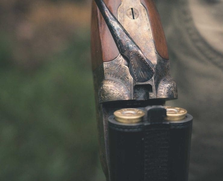 A parker shotgun with a bird hunter in the woods.
