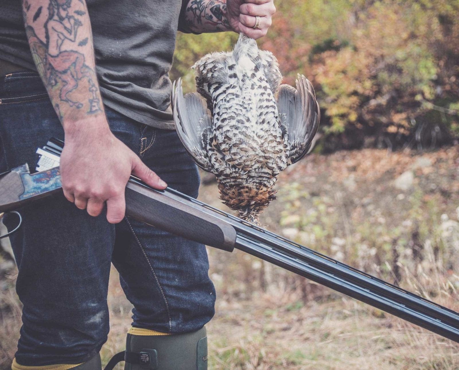 A partridge hunter holds up a ruffed grouse.