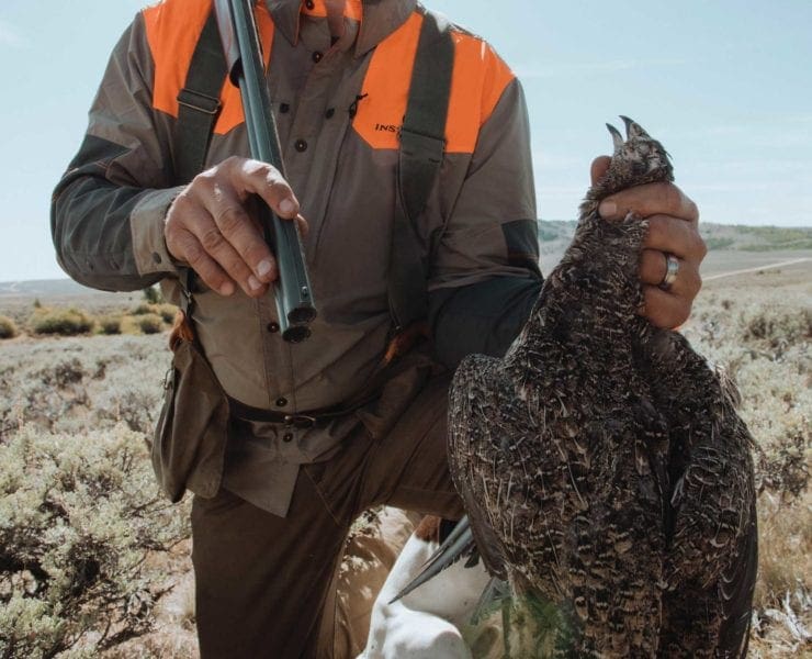 A hunter holds up a Sage Grouse