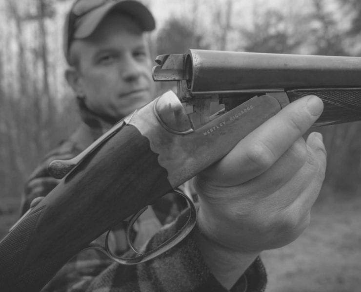 Gregg Elliot posing with a vintage double barrel shotgun