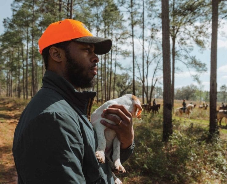 Host of The Gun Dog Notebook Durrell Smith holding his English pointer puppy at a field trial.