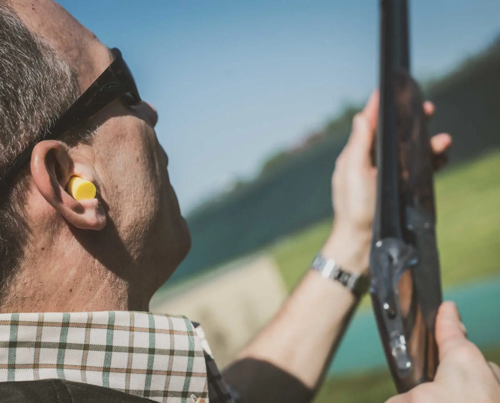 A skeet shooter stands at the ready for a clay pigeon.