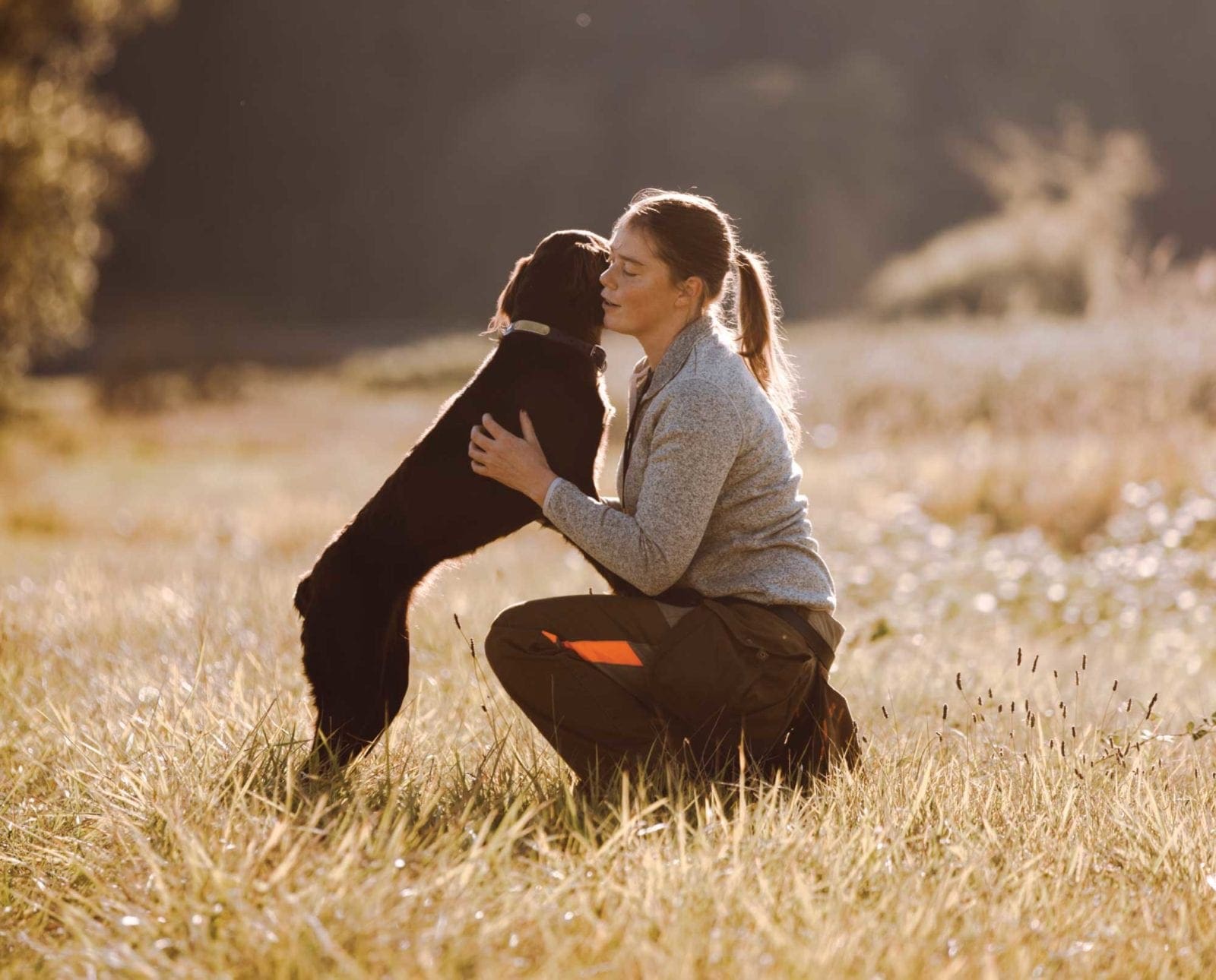 A woman training her first bird dog in a field.