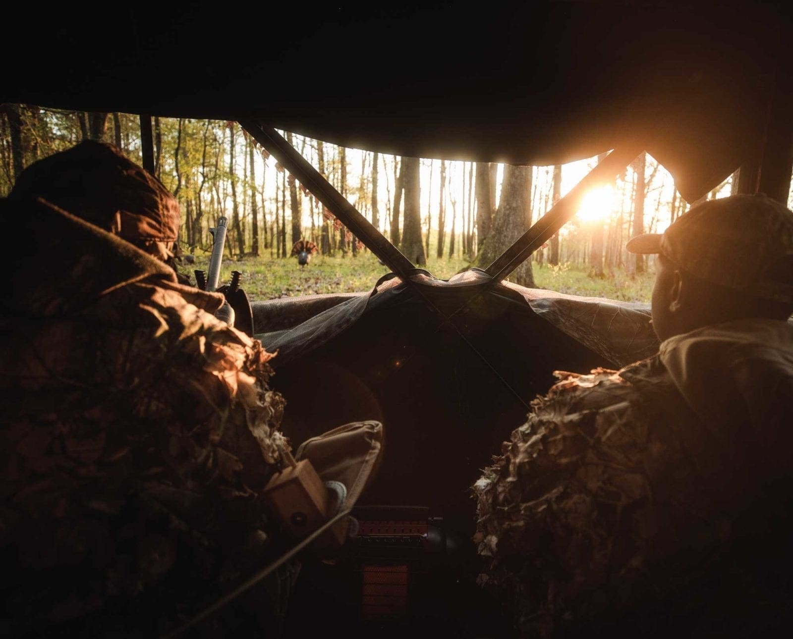 Hunters sit in a turkey blind on a hunt.