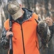 A bird hunter holds a ruffed grouse and a Franchi Affinity.