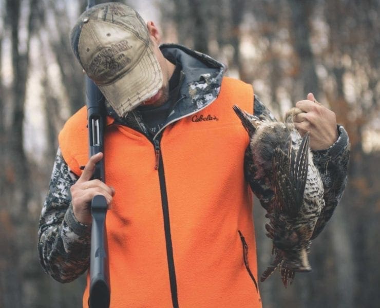 A bird hunter holds a ruffed grouse and a Franchi Affinity.