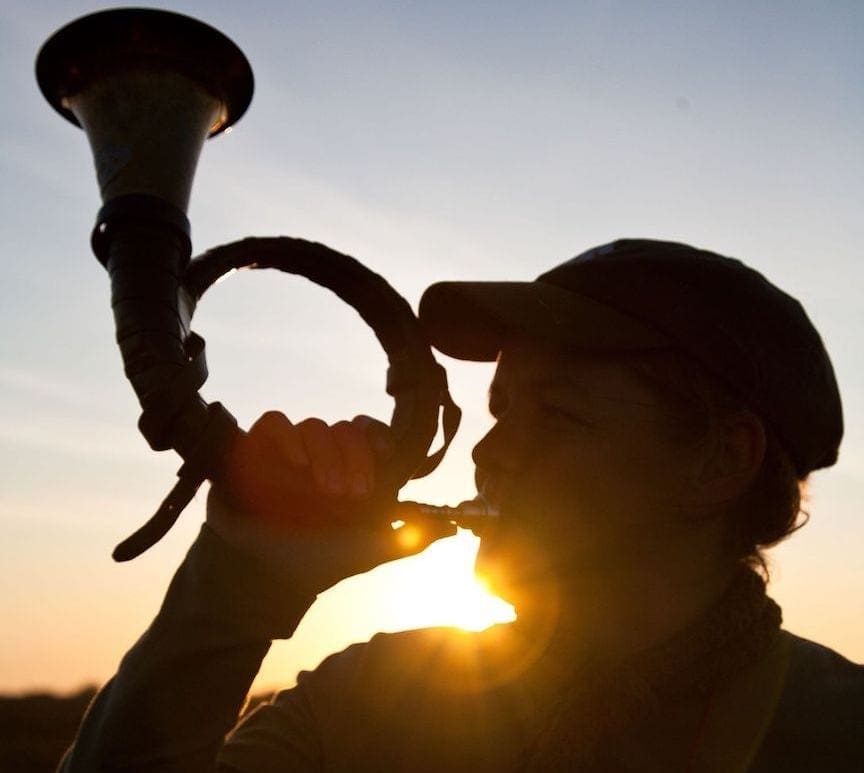 A German hunter blows the traditional hunting horn at sunset