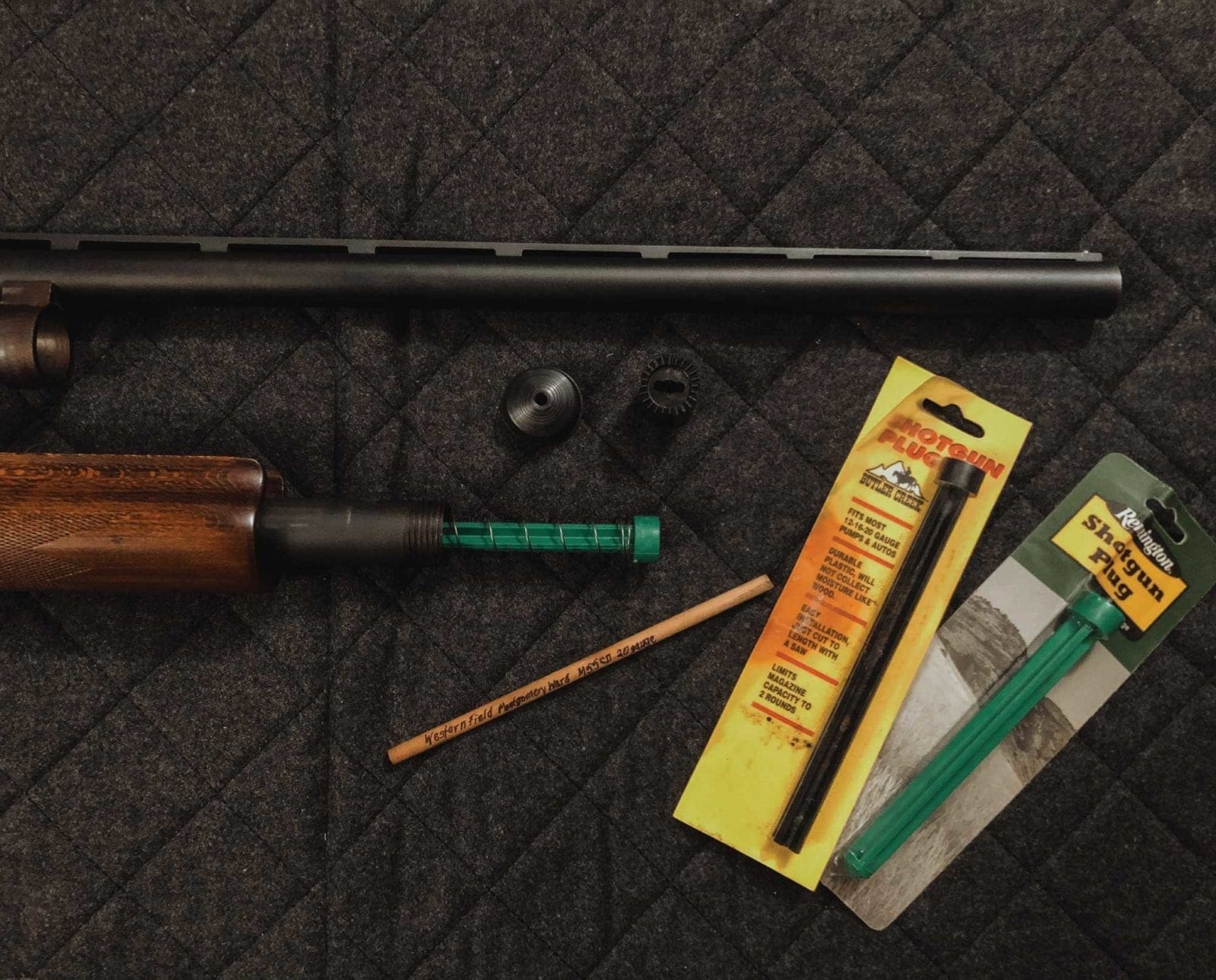 A disassembled shotgun with factory and wooden plugs