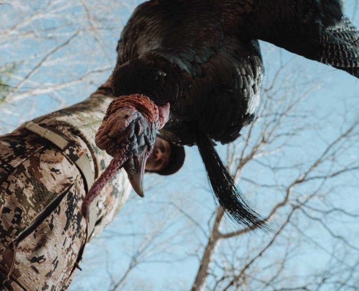 A turkey hunter holds up a long beard Tom