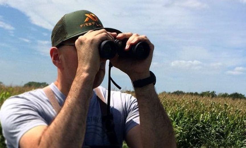 A dove hunter uses binoculars to scout dove fields. 