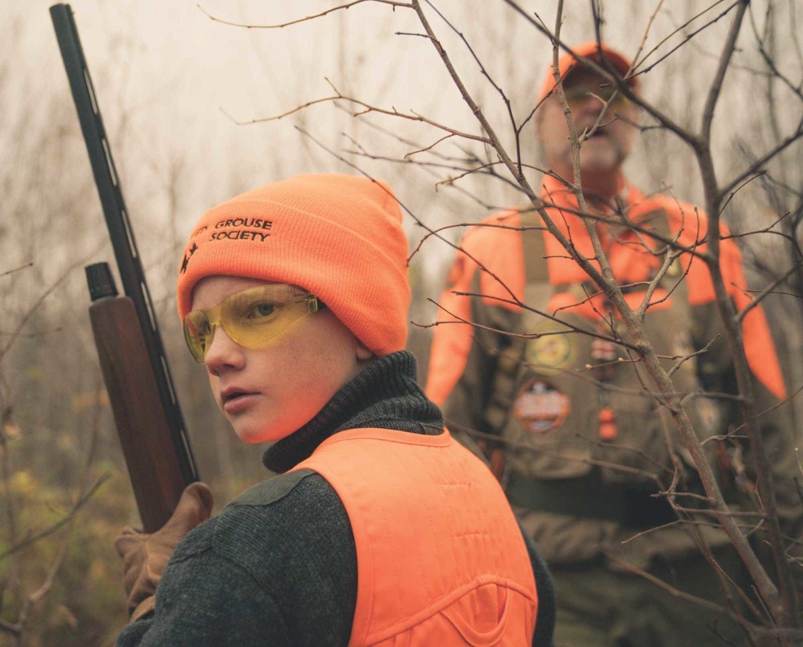 a youth hunter holds a shotgun while hunting grouse and woodcock.