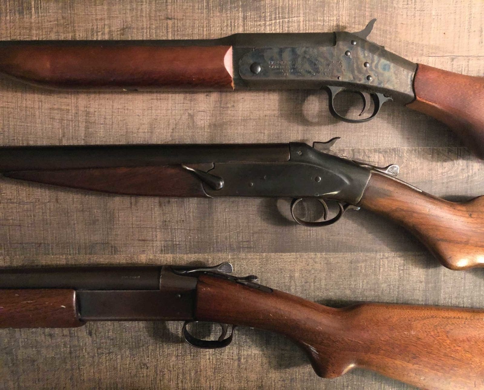 Three single shot shotgun models on a table