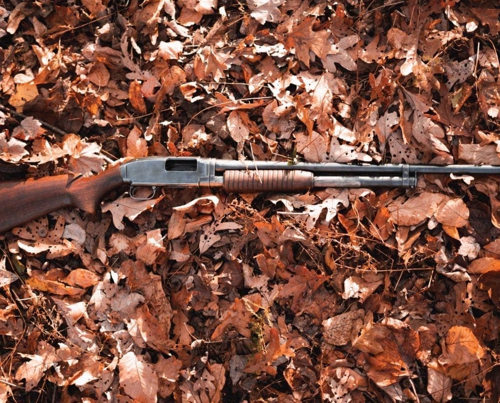 A Model 12 shotgun laid out on the ground 
