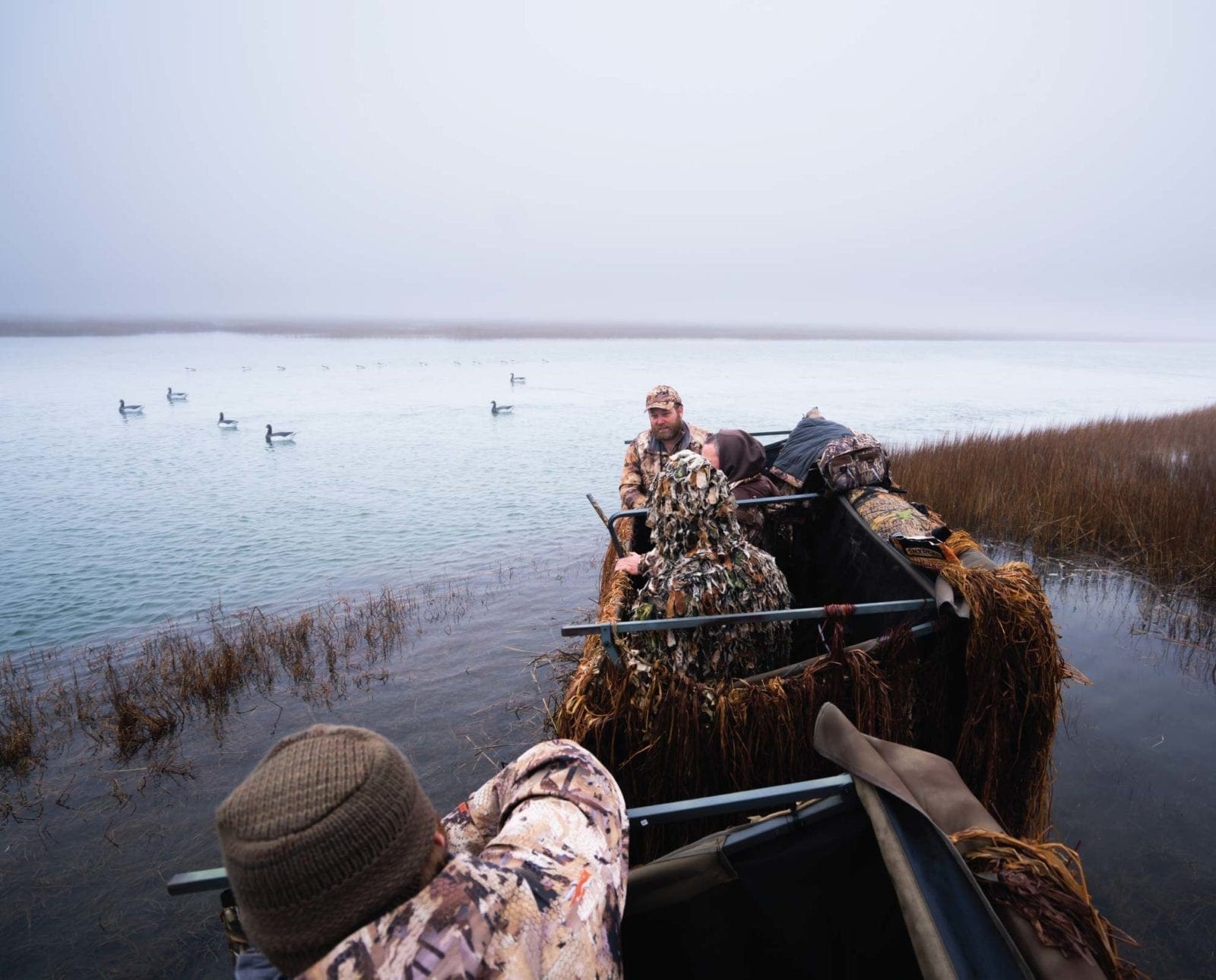 A duck blind beside a spread of decoys for hunting