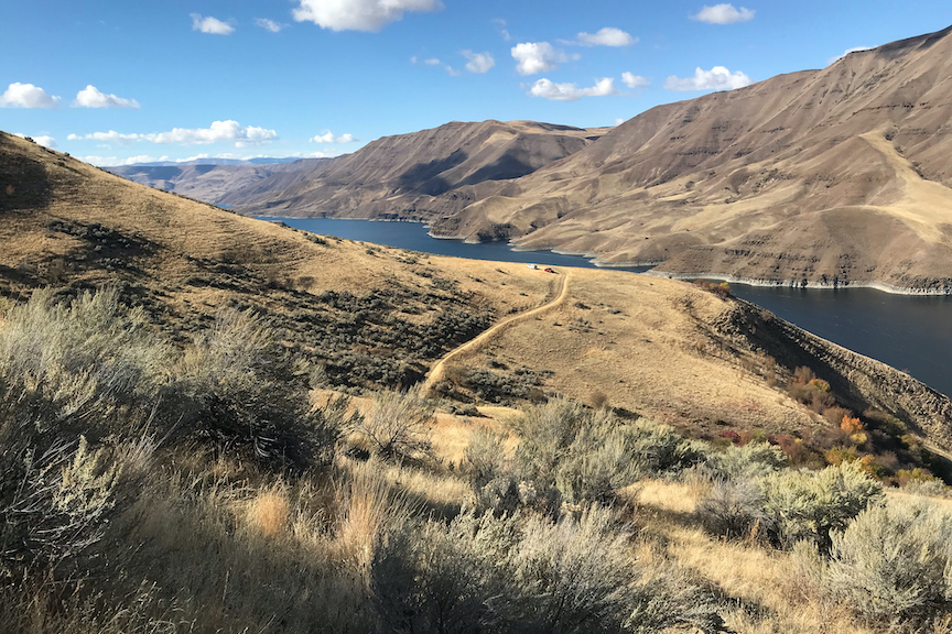 Landscape photo of Hells Canyon with two trucks in the distance