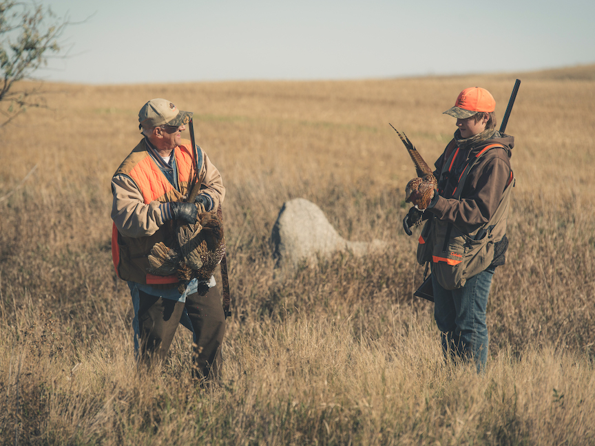 Two pheasant hunters standing in a fall field