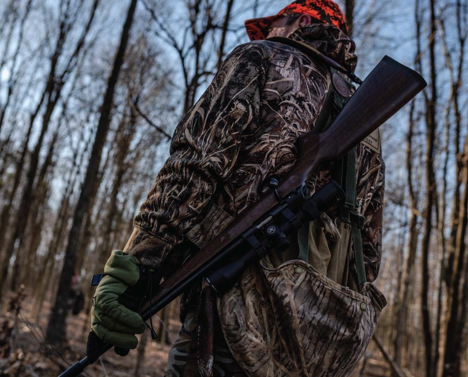 A squirrel hunter stands in the woods with a gun