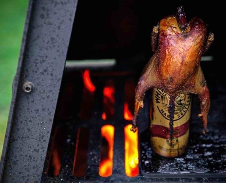 A chukar roasts on a seltzer can over a fire