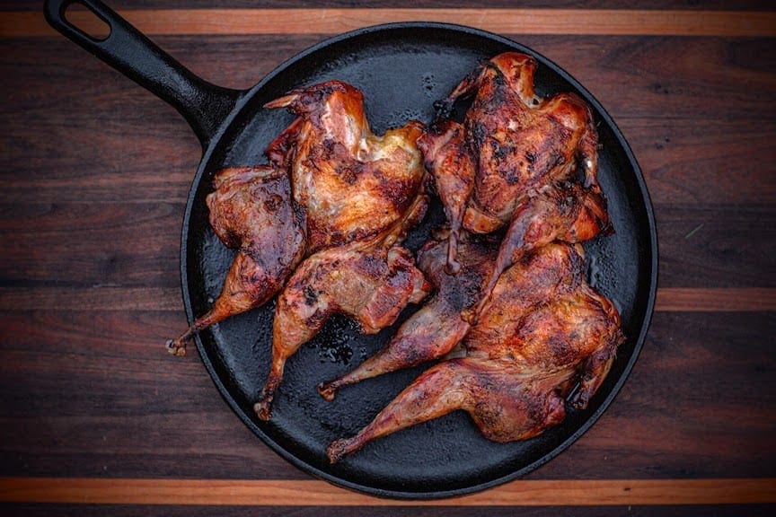 Spatchcocked game birds in a cast iron skillet