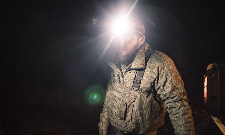 A duck hunter uses a headlamp in the darkness