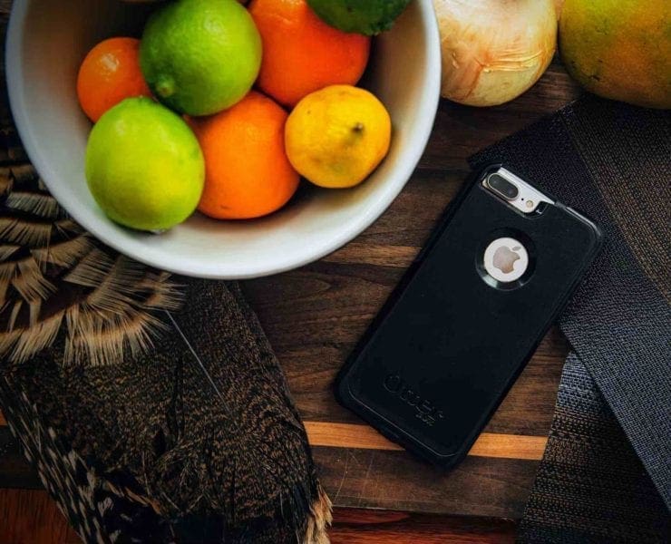 A cell phone on a table setting with fruit