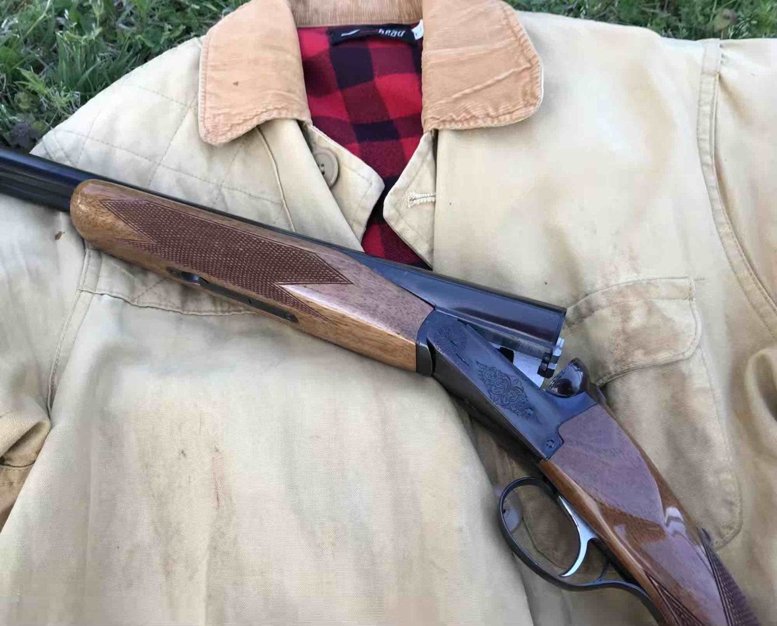 A Browning BSS shotgun laid out on a hunting jacket.