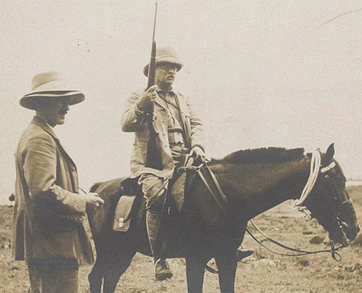 Theodore Roosevelt sits atop his horse with his custom Springfield M1903 rifle.