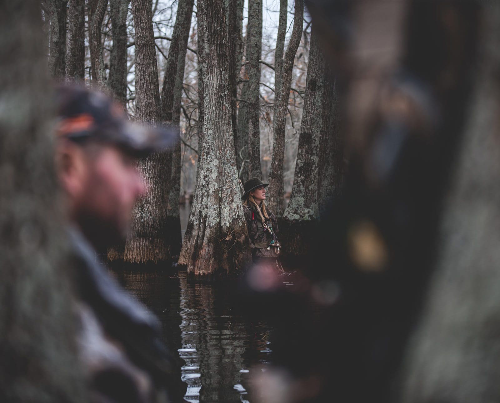 Two duck hunters wait in flooded timber while duck hunting.