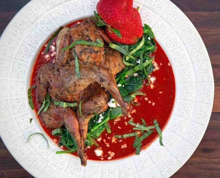 Grilled quail in strawberry-chipotle sauce on a white plate
