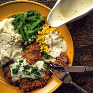 Chicken fried prairie chicken sits on a plate with sides.