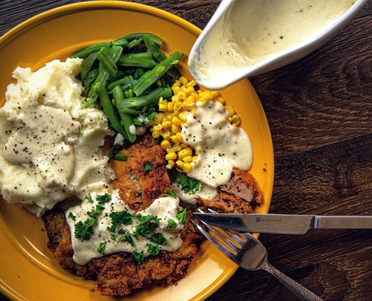 Chicken fried prairie chicken sits on a plate with sides.