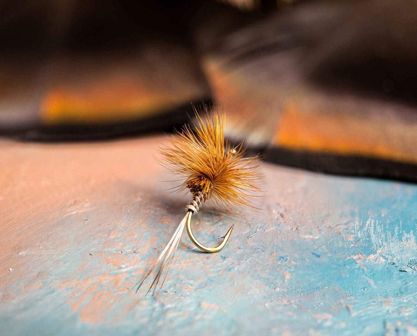 A fly fishing fly made with turkey feathers rests on a table.