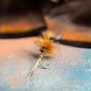 A fly fishing fly made with turkey feathers rests on a table.