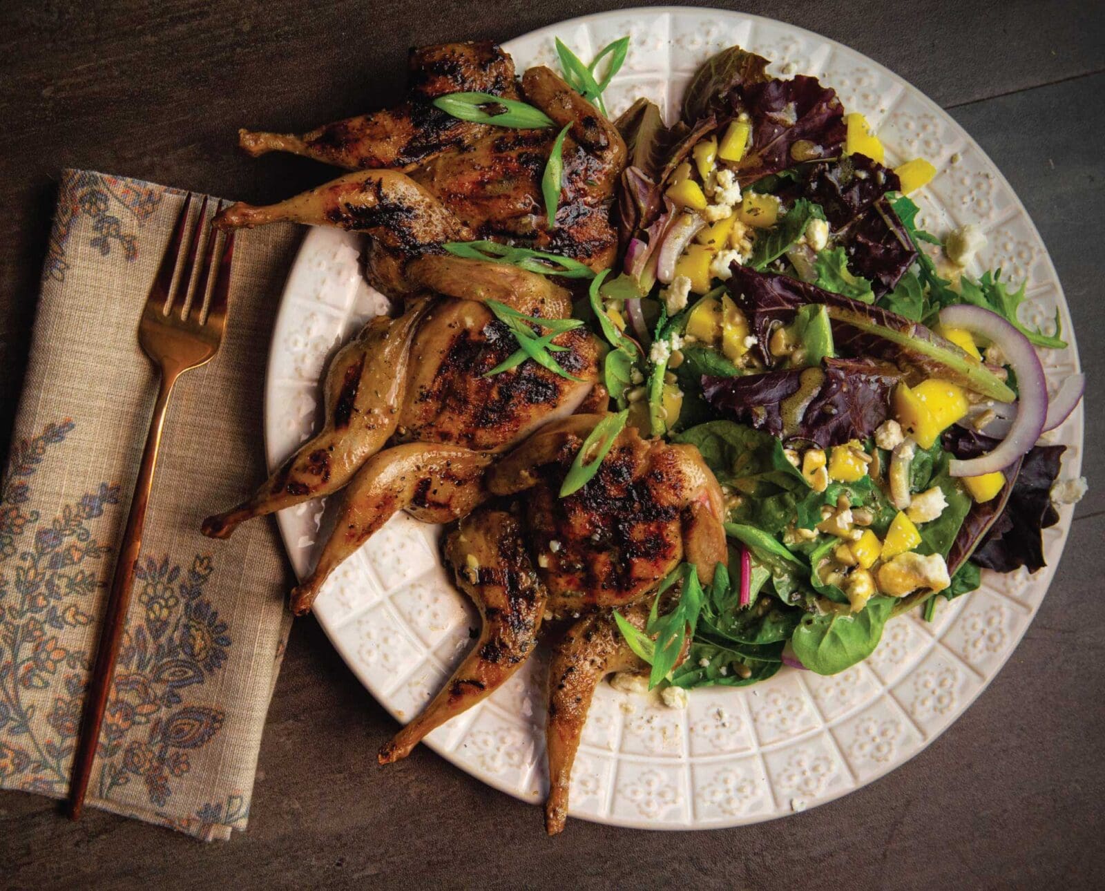 Grilled quail on a plate with salad.