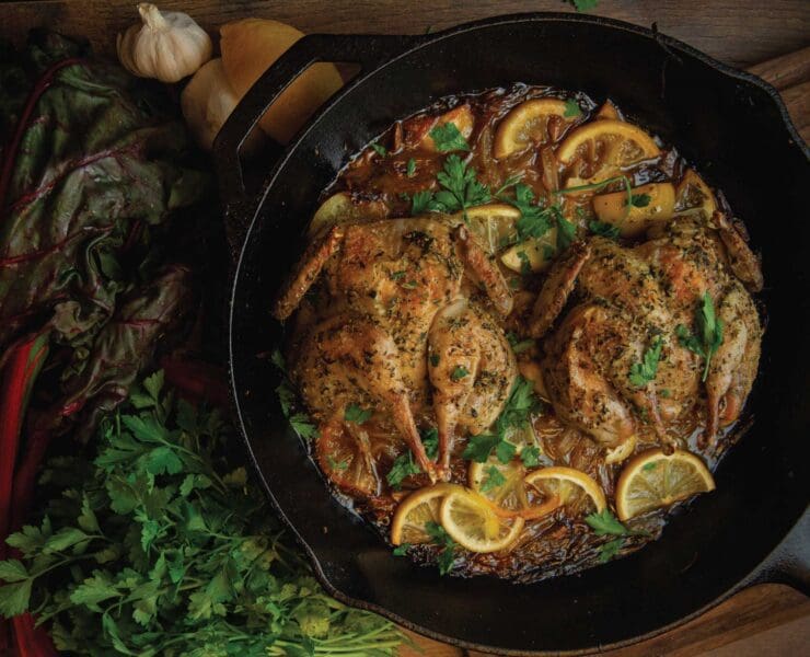 A cast iron skillet with lemon roasted chukar cooking in it