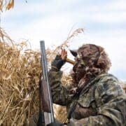 A duck hunter uses a duck call to call in ducks