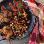Grilled quail in a skillet with a pumpkin side dish