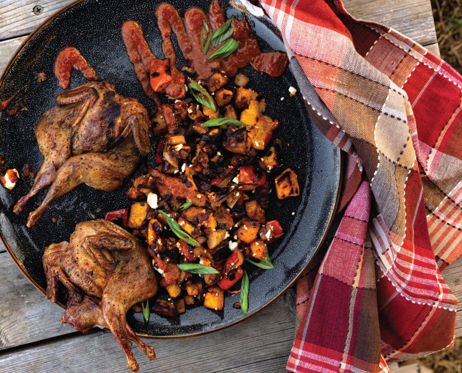 Grilled quail in a skillet with a pumpkin side dish