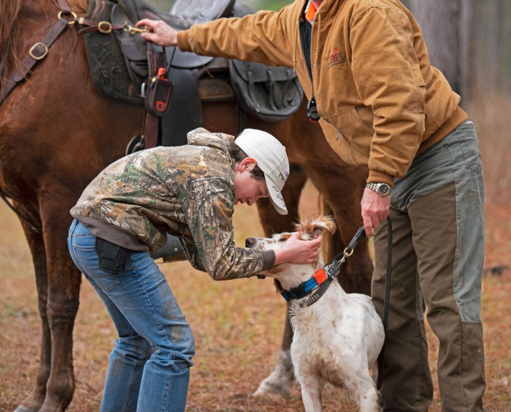A boy pats a bird dog during a Youth Field Trial event
