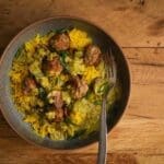 A dish of turkey meatballs served over saffron rice in a creamy poblano sauce on a wooden table background