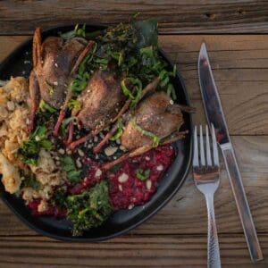 A plate of three whole-roasted doves with a champagne raspberry sauce, served with cauliflower