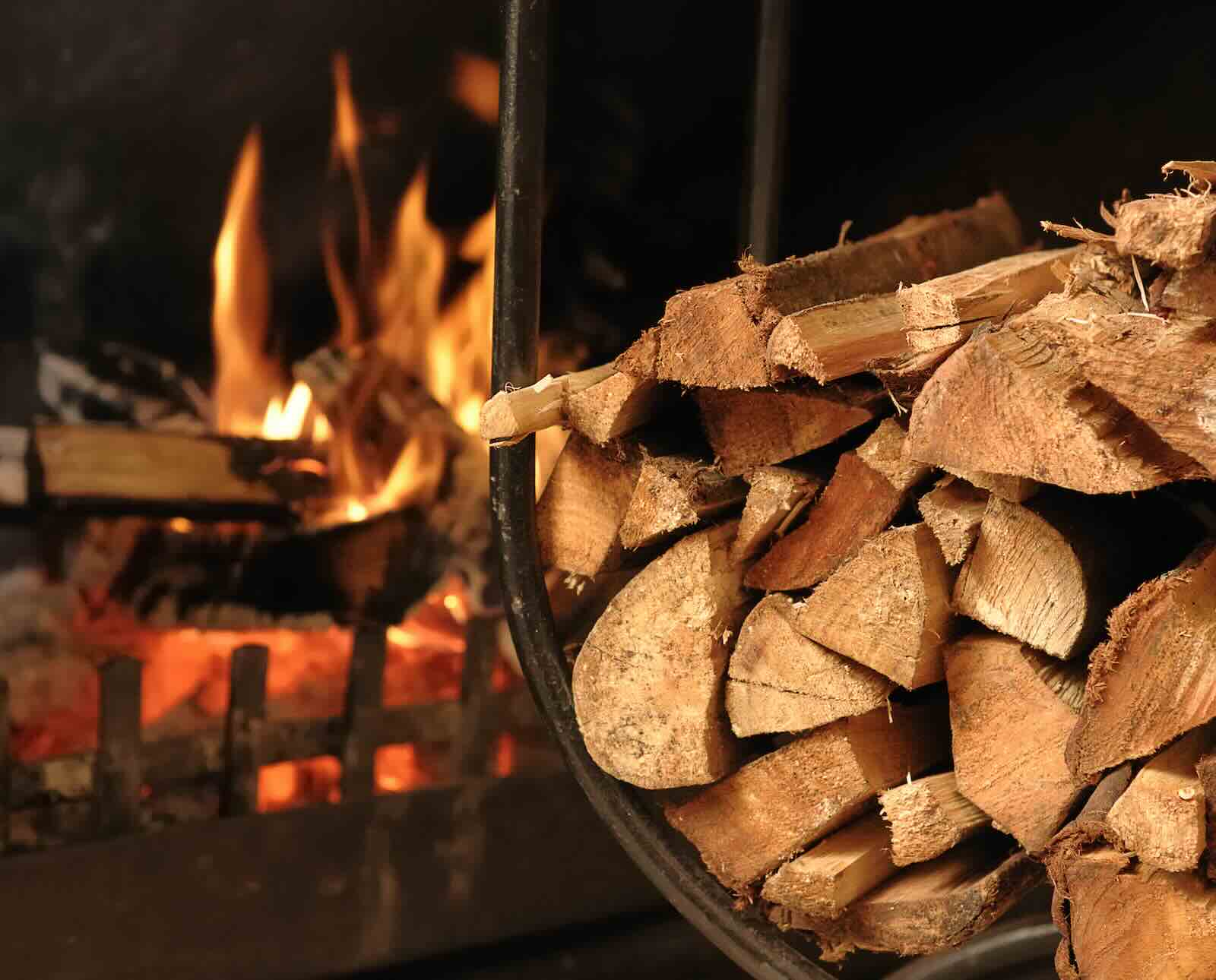 A bundle of split firewood with a fire burning in the background