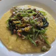 A serving of fried woodcock and yellow grits topped with fresh scallions on a white plate