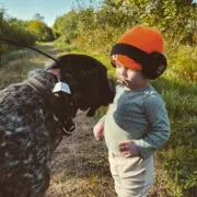 A bird dog with a toddler while out hunting.