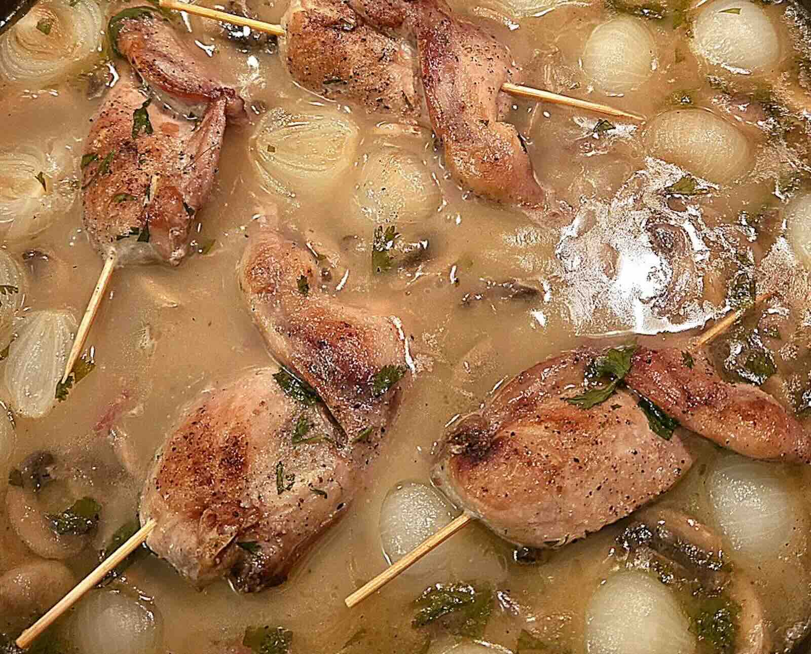 Quail meat on skewers in a wine broth