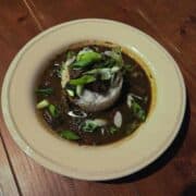 A white dish filled with rice and gumbo on a wood plank background