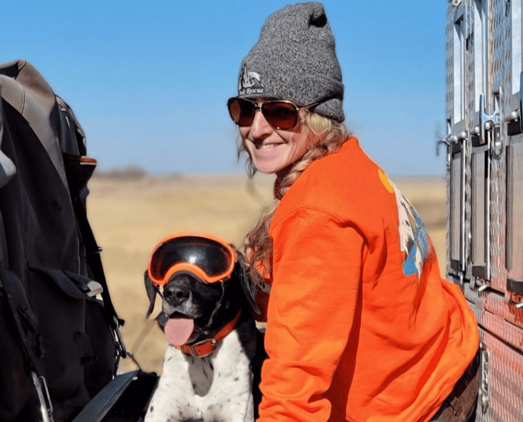 Gina Deem sits on a tailgate with her rescued German Shorthaired Pointer.