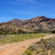 A road winds down grassy and rocky hills on BLM land in Utah.