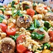 A colorful pasta salad with turkey meatballs, tomatoes, chickpeas, spinach, and orzo pasta.